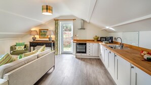 A modern loft apartment with a living room, kitchenette, and a sliding glass door to a garden. - 2 Bed in Dunsop Bridge (oc-w33525) (Dunsop Bridge)