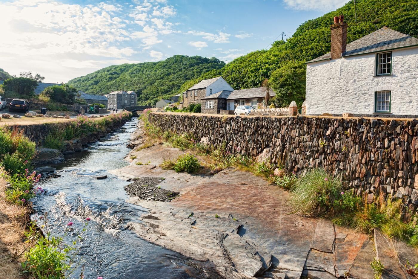 A stone wall, a river, and houses with stone walls and pitched roofs.
