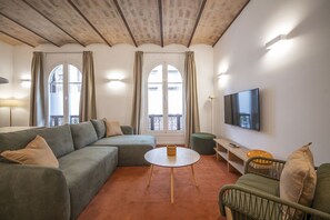 A living room with a sofa, a round table, a TV, and a balcony view. - Modern 3 Bedroom Apartment in Uptown Barcelona (Barcelona)