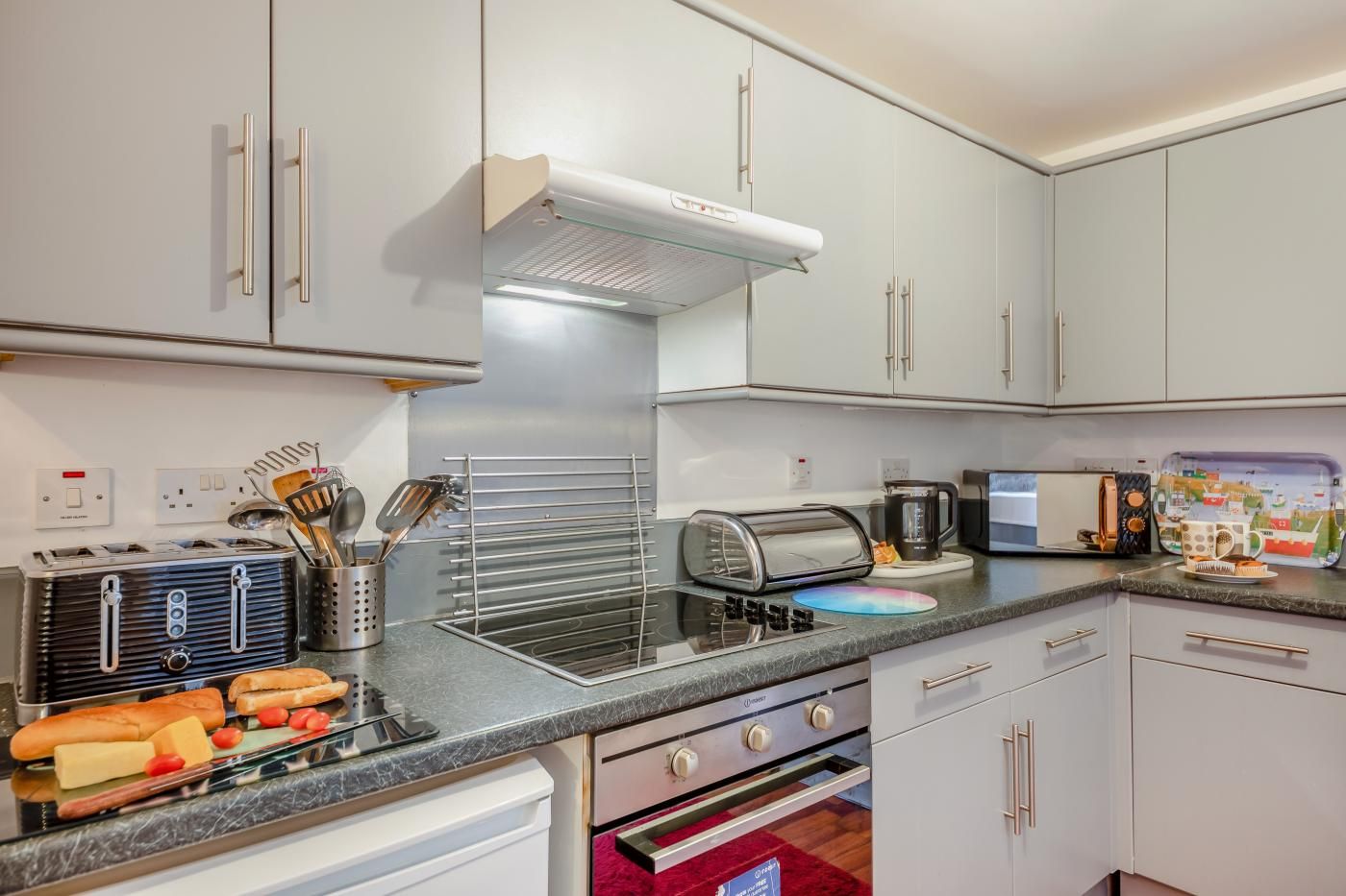A modern kitchen with white cabinets, a built-in oven, a microwave, and a toaster.