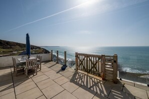 Une terrasse avec une table et des chaises donnant sur la mer.