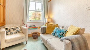 Una sala de estar acogedora con dos sofás, una ventana con cortinas, una lámpara y una cesta en el suelo.