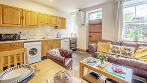 Un espacio habitable compacto con kitchenette, un sofá, una mesa de comedor y una lavadora.