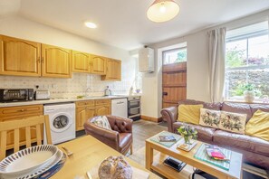 A compact living space with a kitchenette, a sofa, a dining table, and a washing machine.