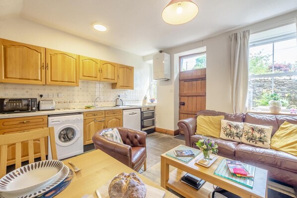 A compact living space with a kitchenette, a sofa, a dining table, and a washing machine.