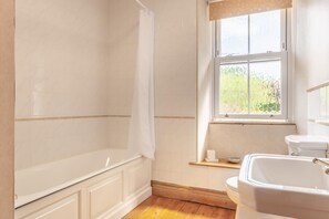 A bathroom with a bathtub, a toilet, and a window.