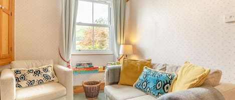 Una sala de estar acogedora con dos sofás, una ventana con cortinas, una lámpara y una cesta en el suelo.