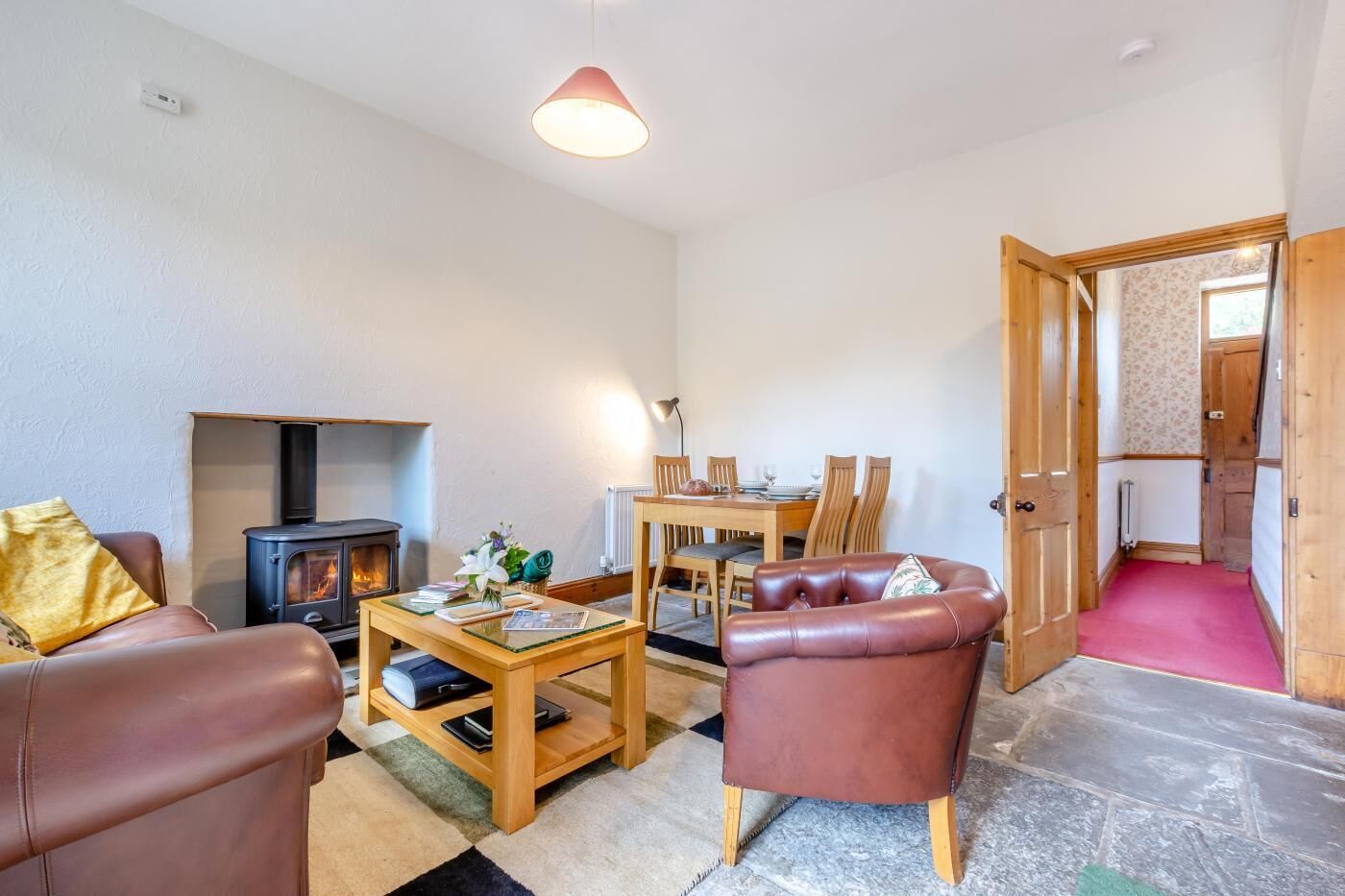 Un salón acogedor con chimenea, sofá de cuero, mesa de comedor y una puerta que da a otra habitación.