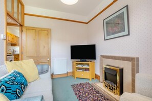 A living room with a sofa, television, fireplace, and a bookshelf. - 2 Bed in Sedbergh (oc-m33975) (Millthrop)