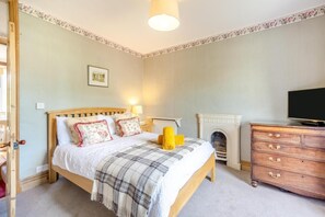 A bedroom with a bed, a dresser, a fireplace, and a television.