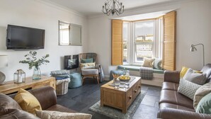 A living room with a sofa, armchair, coffee table, and a television. - 3 Bed in Porthleven (oc-12bayv) (Porthleven)