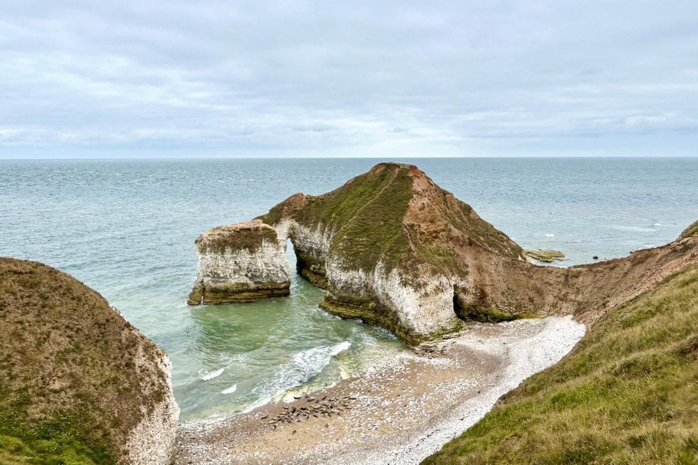 Un paysage côtier caractérisé par une formation rocheuse imposante et une plage.