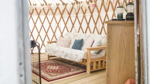 A cozy room with a wooden sofa, a patterned rug, and a lattice wall.