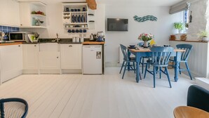 Eine moderne Küche mit weißen Schränken, einer eingebauten Mikrowelle und einem kompakten Kühlschrank.