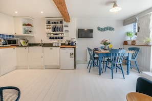 Eine moderne Küche mit weißen Schränken, einer eingebauten Mikrowelle und einem kompakten Kühlschrank.