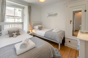 Et soveværelse med to senge, et natbord med lampe, et spejl og en væg med et citat.