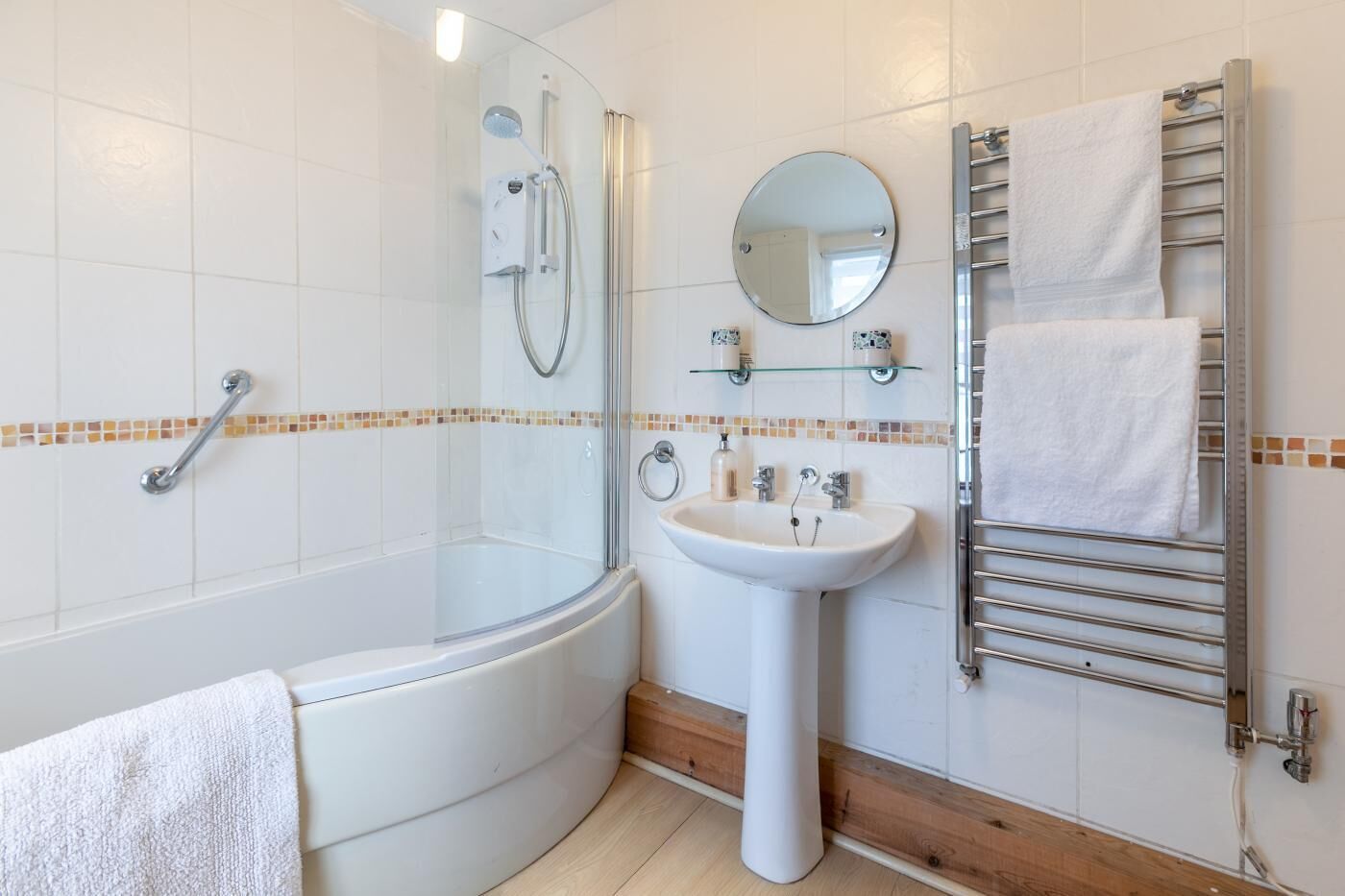 A bathroom with a glass-enclosed shower, a pedestal sink, a towel rack, and a mirror.