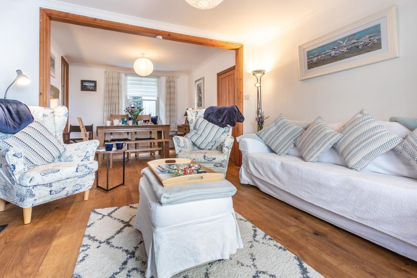 Uma sala de estar com sofá, poltrona, mesa de centro e canto de jantar com mesa e cadeiras.