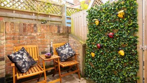 Una panca di legno con una bottiglia e fiori, un muro di mattoni e un muro verde con decorazioni.