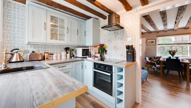 Una cucina moderna con mobili azzurri, un'isola in legno e travi a vista.