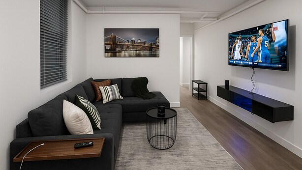 Una sala moderna con un sofá seccional, un televisor montado y un cuadro de un paisaje urbano.
