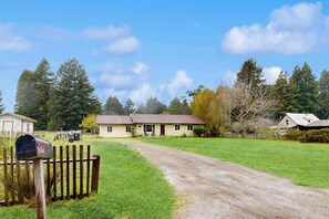 A rural house with a dirt driveway leading to a front porch, surrounded by a wooden fence and a mailbox. - Family Favorite with Large Yard and BBQ (Fort Bragg)