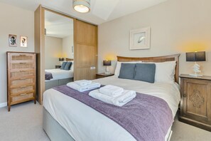 A hotel room with a large bed, two bedside tables, a wooden wardrobe, and a mirror. - 5 Bed in Porthleven (oc-merlyn) (Porthleven)