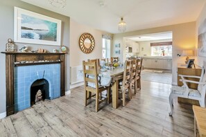 A spacious dining area with a fireplace, wooden dining table, and chairs. - 5 Bed in Porthleven (oc-merlyn) (Porthleven)