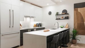 A modern kitchen with a central island, white cabinetry, and a wooden floor. - Revy Retreat in Mackenzie Village (Revelstoke)