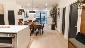 A modern kitchen with a central island, dining area with chairs, and a large window providing a view of the city. - Revy Retreat in Mackenzie Village (Revelstoke)