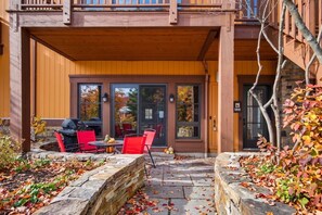 A covered patio with outdoor seating, a barbecue grill, and a stone planter. - Aux Étoiles EMG: Ski In/Out at Soleil Express (Mont-Tremblant)
