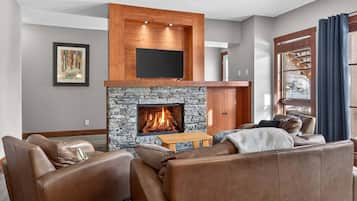 A living room with a stone fireplace, leather sofas, and a mounted TV.