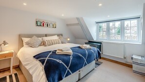 Une chambre à coucher avec un lit, une table de chevet, une fenêtre et un radiateur.