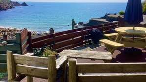 Um deck de madeira com vista para o mar, uma mesa e um guarda-sol.