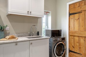 A compact kitchen with a built-in washing machine, a microwave, and a sink. - 3 Bed in Fulbeck (oc-v33643) (Fulbeck)