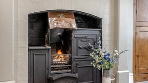 A traditional fireplace with a metal cover, a decorative handle, and a vase with flowers. - 3 Bed in Fulbeck (oc-v33643) (Fulbeck)