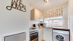 A compact kitchen with a built-in oven, microwave, and washing machine. - 2 Bed in Walcott (oc-2282) (Walcott)