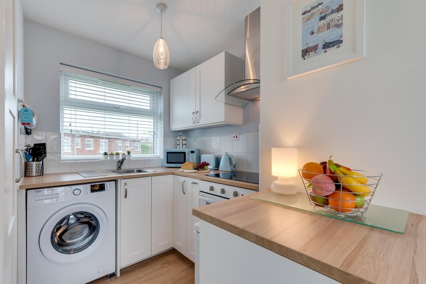 A modern kitchen with a washing machine, microwave, and kettle.