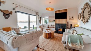Un amplio salón con chimenea, ventanas grandes y una zona de estar acogedora.