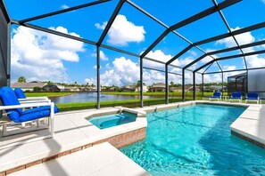 A swimming pool with a glass enclosure, blue lounge chairs, and a view of a residential area. - Poolside 5BR Escape with Pool Table & Parking (Kissimmee)