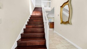A wooden staircase with white railings leading to a second-floor landing. - Poolside 5BR Escape with Pool Table & Parking (Kissimmee)