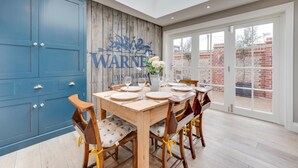 Een eetgedeelte met een houten tafel voor vier personen, blauwe kastjes en een muurschildering.
