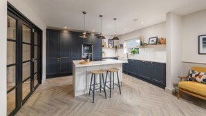Een moderne keuken met donkere kastjes, een wit kookeiland en barstoelen.