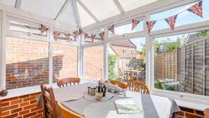 Una veranda con parete in mattoni, un tavolo e sedie, e bandiere britanniche.