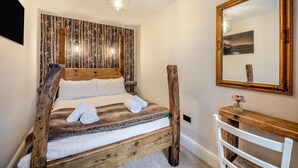 Une chambre avec un lit en bois, un grand miroir et un mur recouvert de lattes de bois verticales.