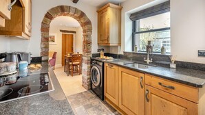 Une cuisine moderne avec une arche en pierre, des armoires en bois, des comptoirs en granit et une grande fenêtre.