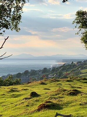 A coastal landscape with rolling hills, a view of the sea, and a distant mountain range. - 3 Bed in Barmouth (oc-wah701) (Barmouth)
