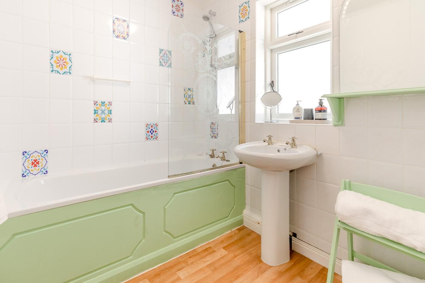 A bathroom with a bathtub, a sink, a mirror, and a window.