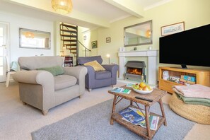 A living room with two sofas, a fireplace, a television, and a small table with magazines and fruit. - 2 Bed in Helford (oc-hcview) (Helford)