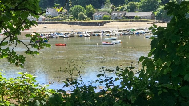 A riverside view with boats docked, a sandy beach, and houses in the background. - 2 Bed in Helford (oc-hcview) (Helford)